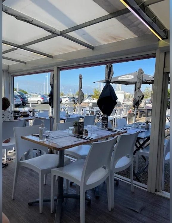 La terrasse couverte, tables dressées, ouverte sur le port des Minimes